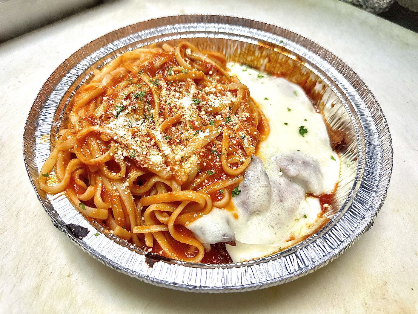 Chicken parmigiana with pasta in tomato sauce, topped with mozzarella