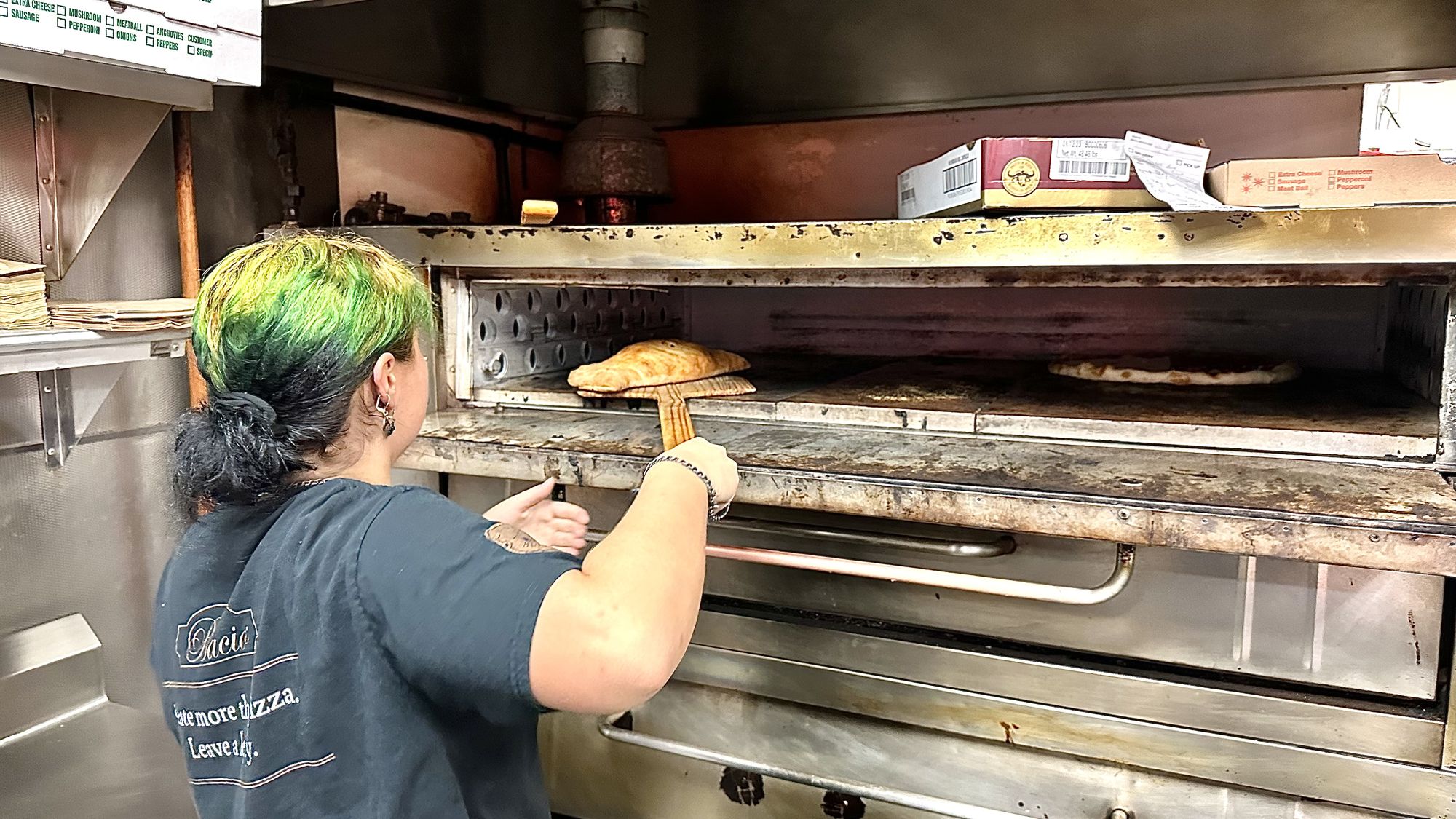 Pulling a pizza out of the deck oven on a wooden peel