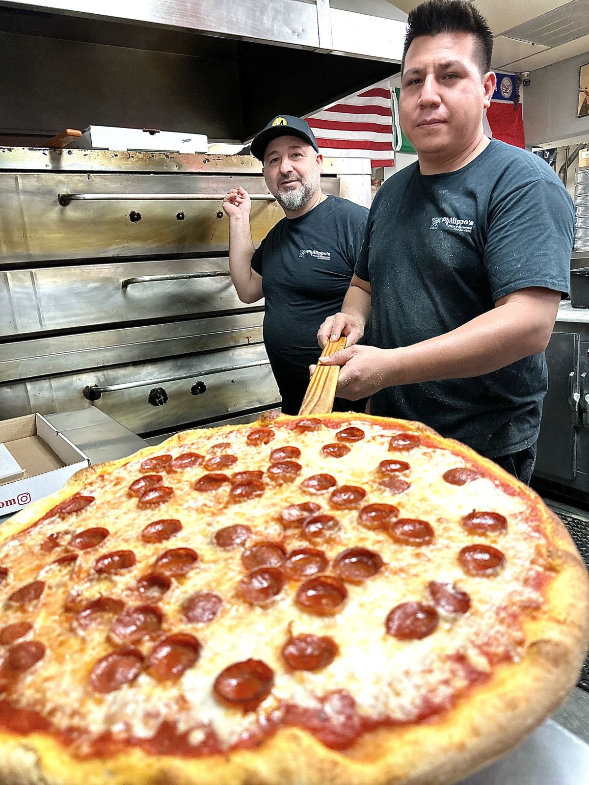 A whole pepperoni pie on the wooden peel, fresh from Phillippo's oven