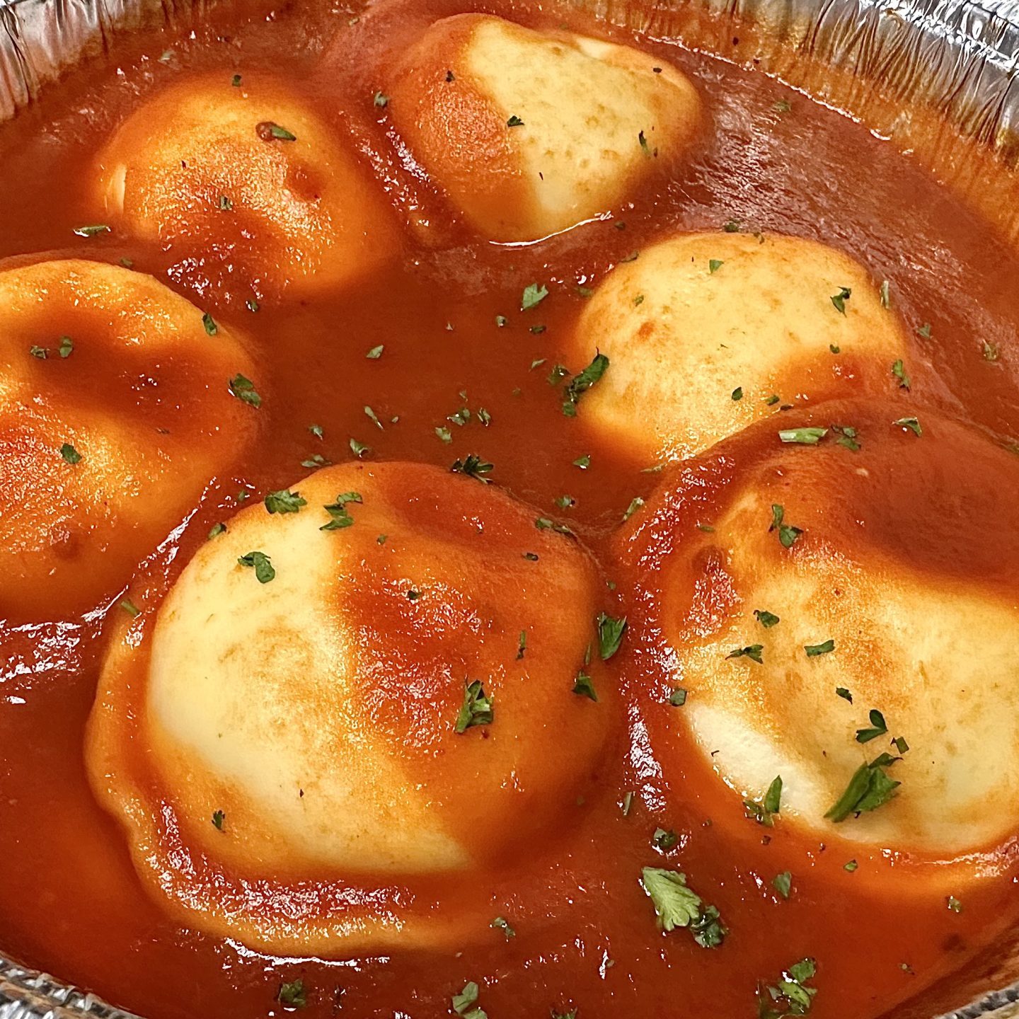 Five Ravioli In Tomato Sauce, Garnished With Herbs, Served In A Foil Container.